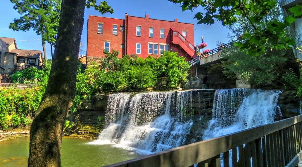 Chagrin Falls is a natural waterfall located in the heart of the village of Chagrin Falls, Ohio on the Chagrin River with a drop of approximately 20 feet and surrounded by scenic parkland with hiking trails, picnic areas and a covered bridge. One of the most prominent buildings in the area is the red brick Chagrin Falls Popcorn Shop which is located next to the waterfall.