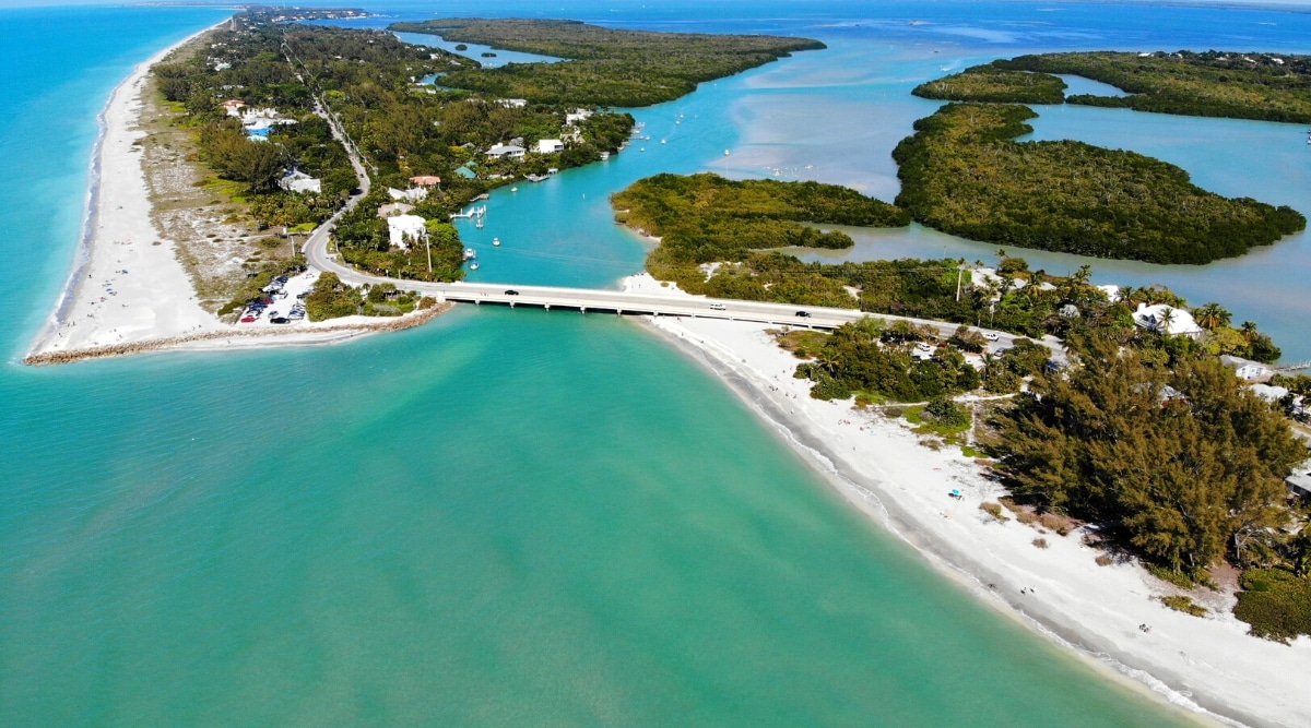 The Highway Bridge between Captiva Island and Sanibel Island in Lee County, Florida is a scenic and popular attraction for visitors to the area. An aerial view of the bridge showcases the stunning turquoise waters of the Gulf of Mexico as the bridge stretches across the water connecting the two islands. The view from above also reveals the lush greenery and natural beauty of the islands.