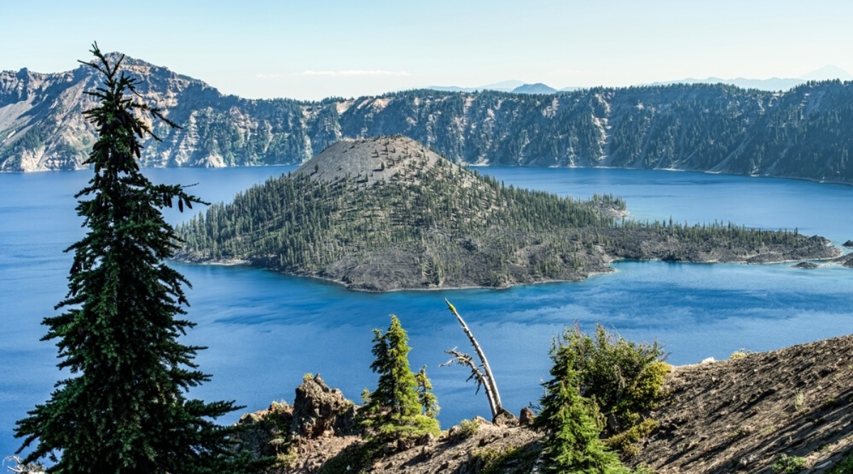 Crater Lake is a deep blue lake located in the caldera of an ancient volcano in Oregon, with strikingly clear waters due to its remote location and lack of inflow rivers, surrounded by beautiful mountain scenery.