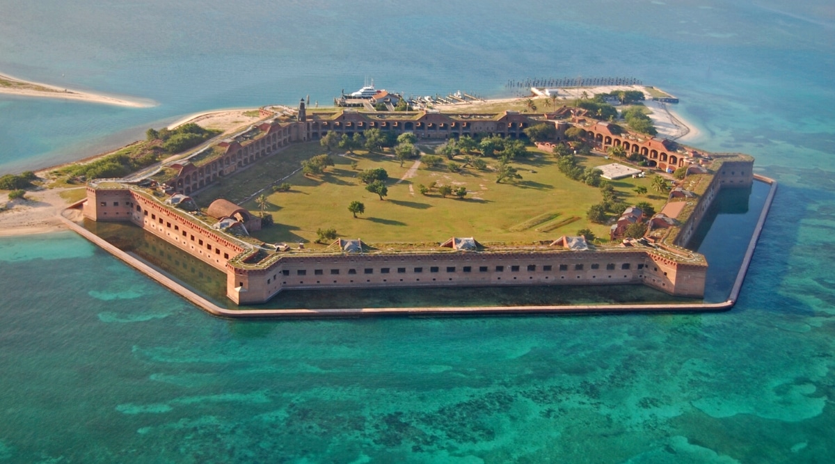 Dry Tortugas National Park is located 70 miles west of Key West, Florida, and consists of seven small islands and protected coral reefs. It is home to the 19th century Fort Jefferson, which was once used as a military prison during the Civil War. The park's most iconic feature is its unique 150-foot-tall, hexagonal brick water tower that was once used as a lighthouse.