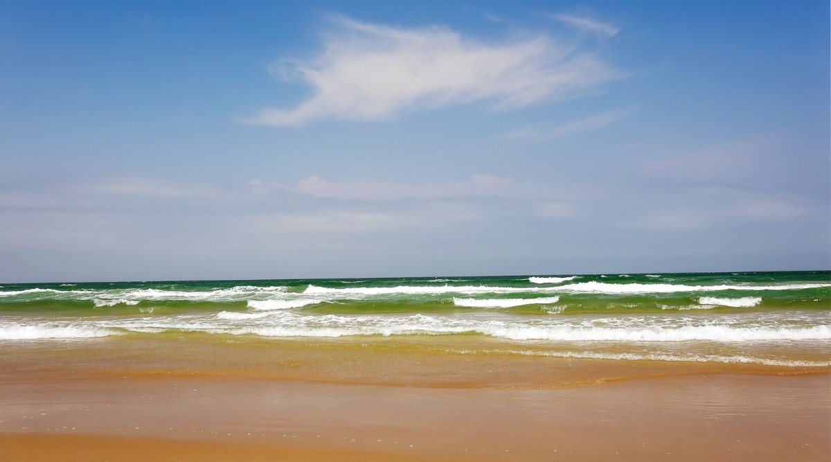 Isla Blanca Beach is a popular Gulf Coast beach destination in Texas known for its soft, white sand, and clear turquoise waters. View of green and white waves with golden sand.