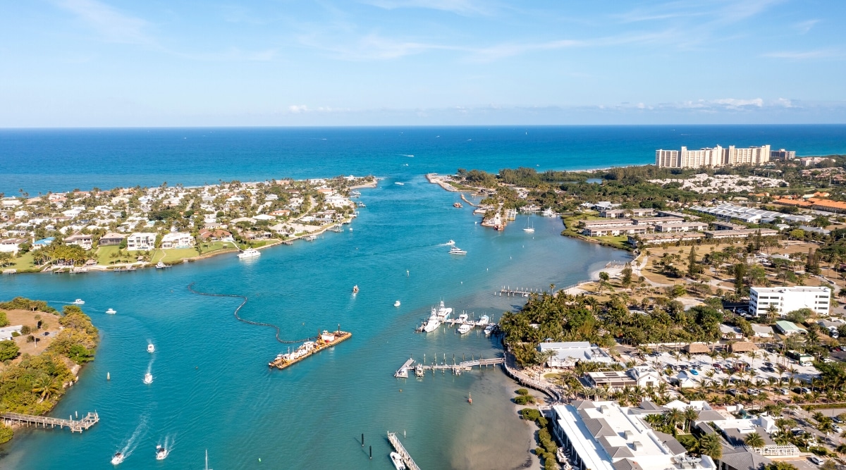 Jupiter Beach is a beautiful and secluded beach located in Jupiter, Florida, known for its clear blue waters, soft sand, and peaceful atmosphere. Views from above of magnificent waters and coastlines, as well as piers, marinas, and floating white yachts in bays.