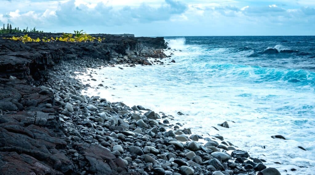 Kaimu Beach is a black sand beach located on the southeastern coast of Hawaii's Big Island, created by a volcanic eruption. The beach offers scenic views of the ocean and nearby coconut groves.