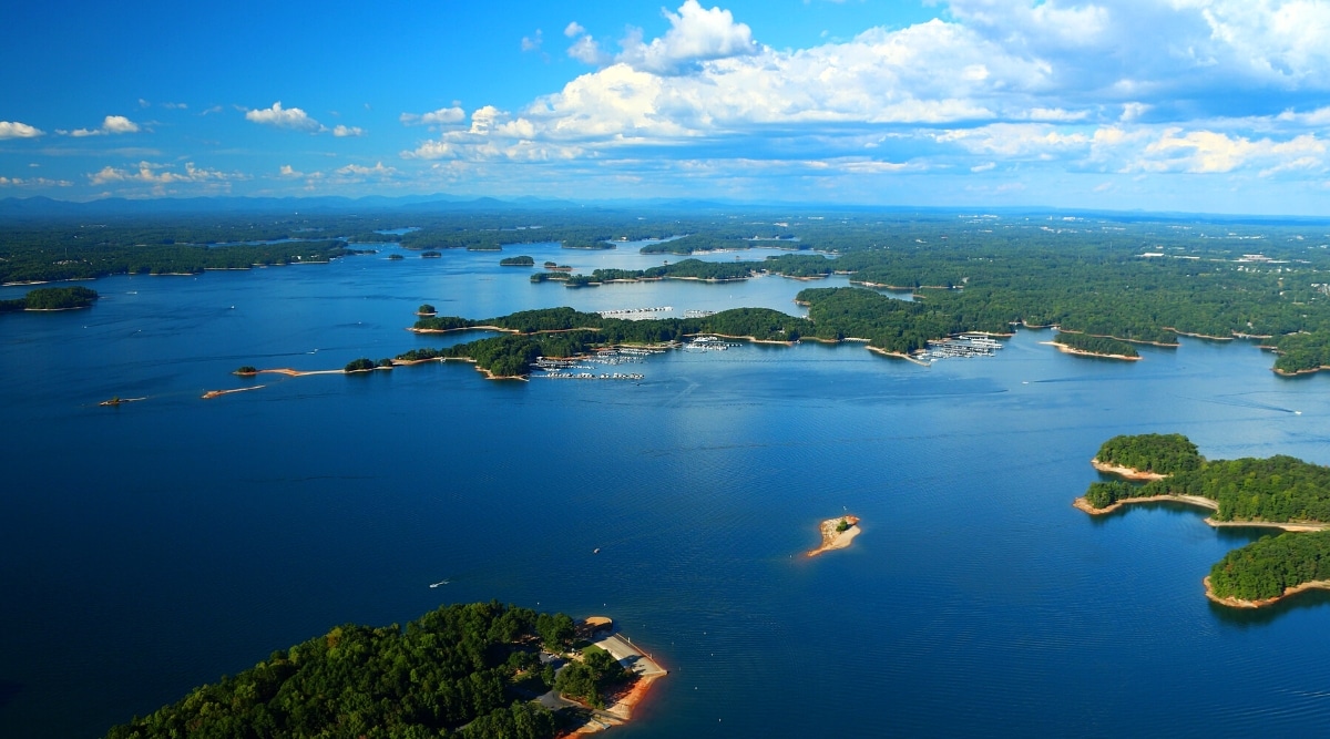 Lake Lanier is a man-made lake in Georgia. The lake spans over 38,000 acres and has over 690 miles of shoreline. Top view of blue waters and beautiful landscapes with green forests.