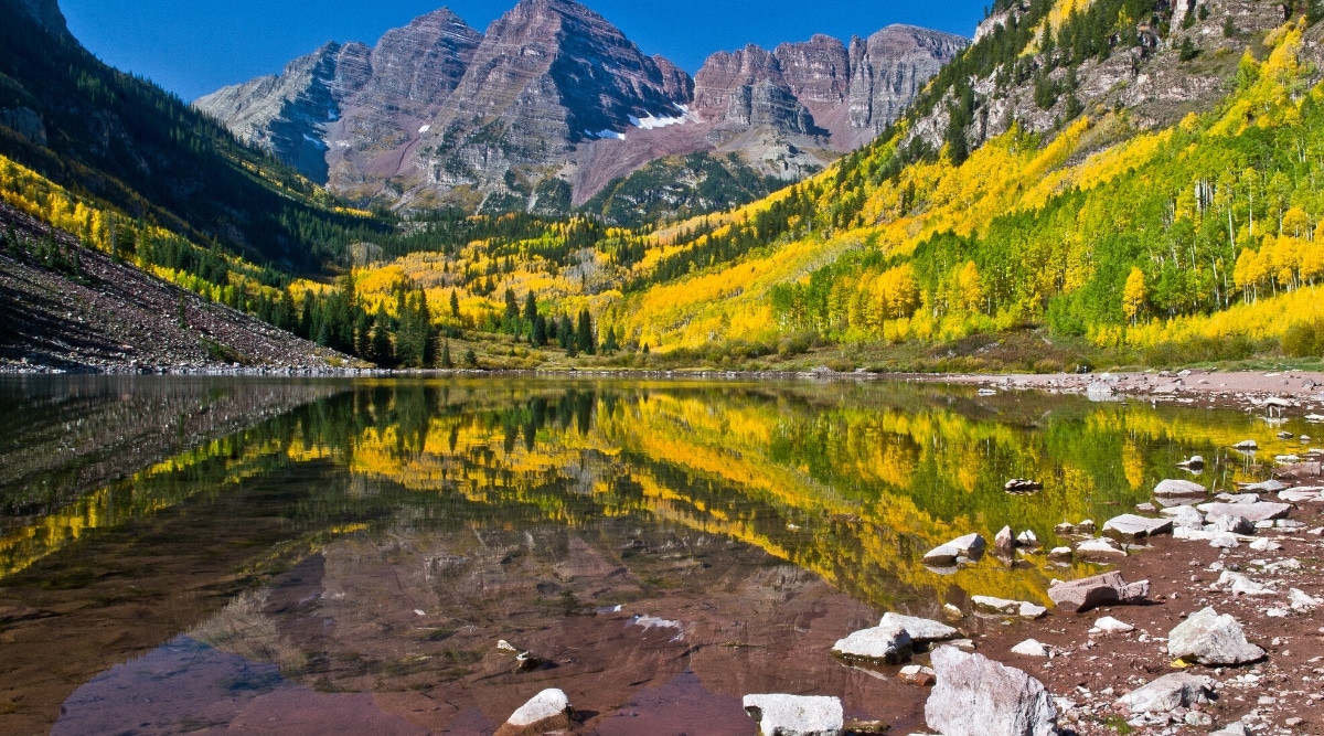 Maroon Lake is a natural lake located in the Maroon Bells-Snowmass Wilderness area near Aspen, Colorado, USA. The lake is surrounded by the stunning Maroon Bells mountain peaks, which are reflected in the crystal clear waters of the lake.