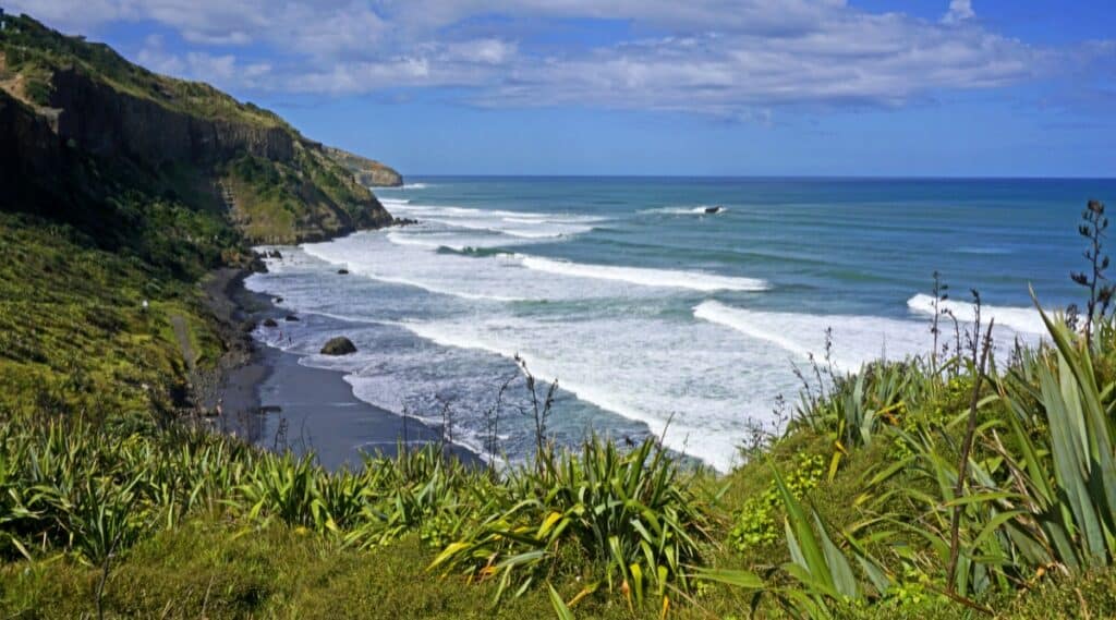 Muriwai Beach is a popular black sand beach located on the west coast of the Auckland region in New Zealand. Muriwai Beach is surrounded by steep cliffs and hills, offering scenic views.