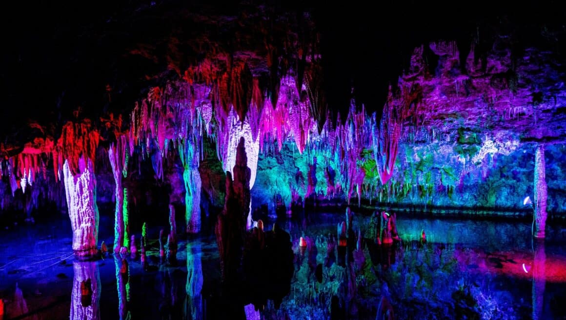 Missouri Cave Meramec Cavern with Lighted caves shining in several different colors. The cave is illuminated in red, purple, pink, blue, and green lighting for the cavern tour.