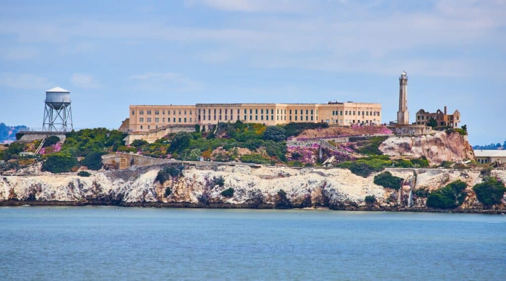 Close up view of the western shores of Alcatraz Island on a sunny day with calm seas and mild cloud cover.