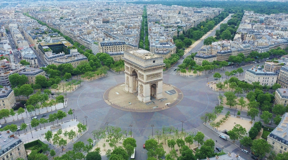 The Arc de Triomphe photographed from above in Paris France on a sunny day, illustrating the twelve roads leading to and from it.