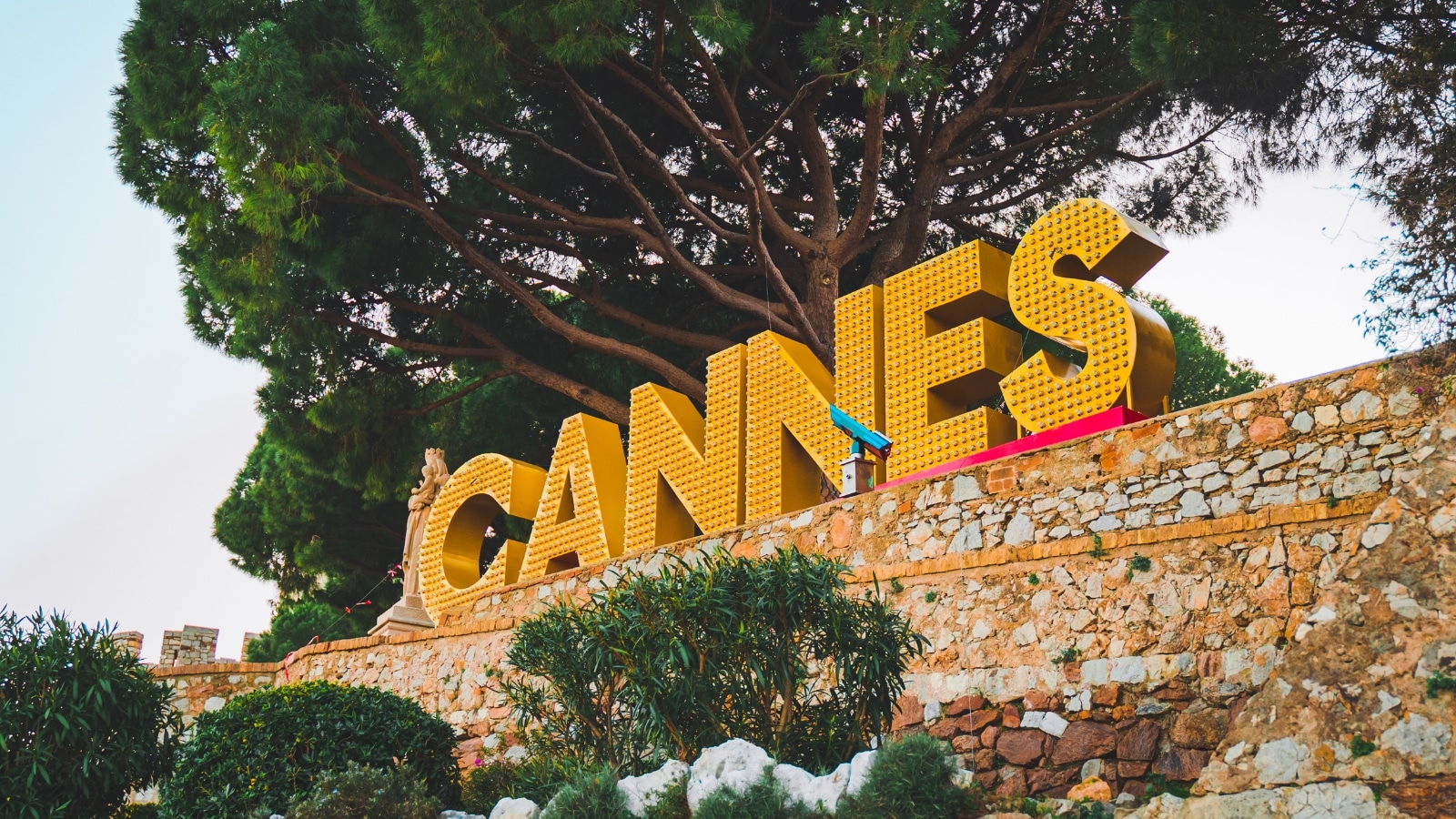 The Cannes hilltop sign with a statue to the left of it in Cannes France.