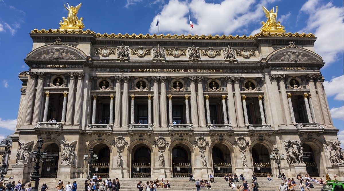 The Opera National de Paris exterior front steps filled with tourists on a clear sunny day in Paris France.