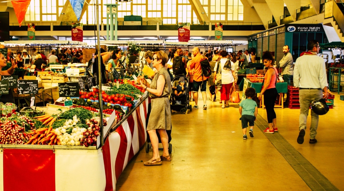 The Halles du Boulingrin in Reims France hosts a food market on Wednesdays, Fridays, and Saturdays, and is filled with tourists and locals shopping for fresh produce.