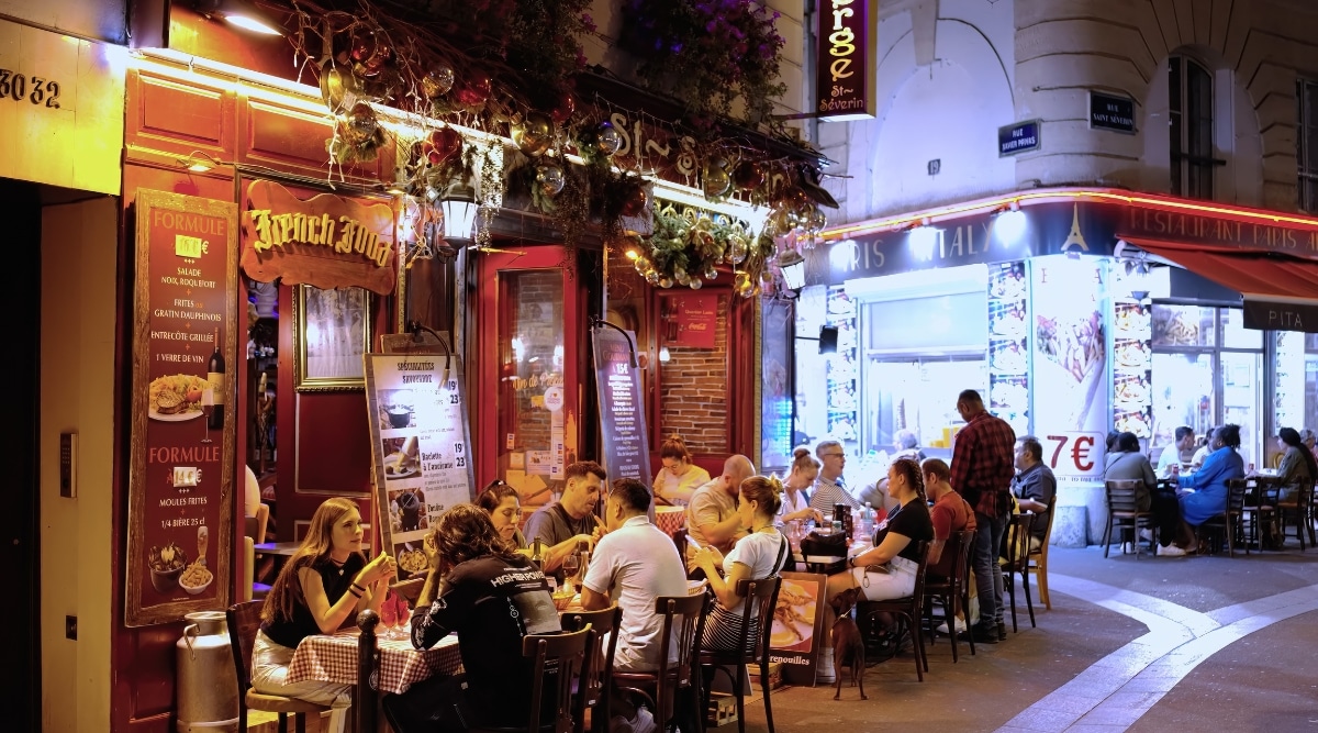 A small French cafe filled with tourists at night in the Latin Quarter district in Paris, France,