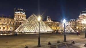 Louvre museum and pyramids illuminated at night.