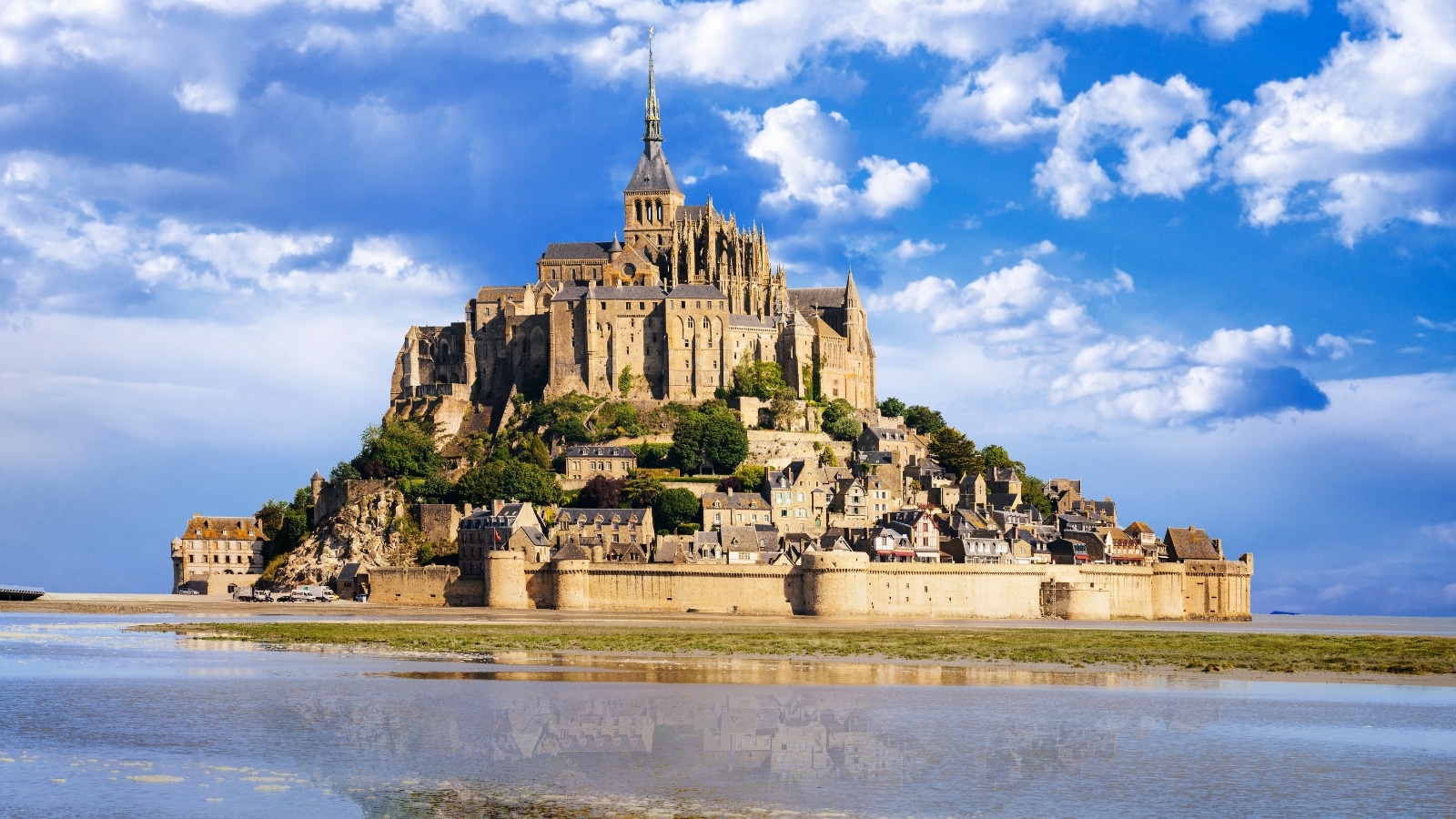 Mont Saint Michel photographed on a clear sunny day with white puffy clouds.