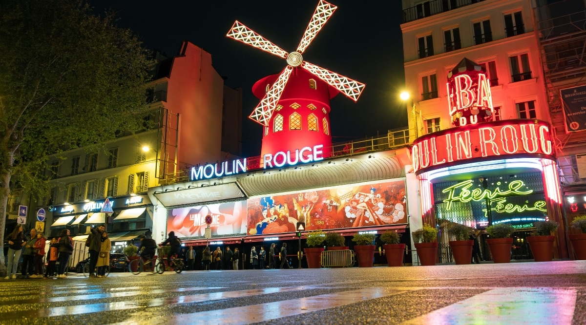 The Moulin Rouge nightclub, light up at night with tourists lined up to get in. 