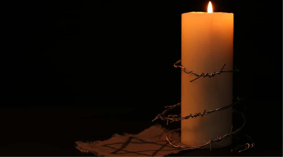 A burning candle with barbed wire loosely wrapped around it and a Star of David indicating a memorial for the Holocaust.