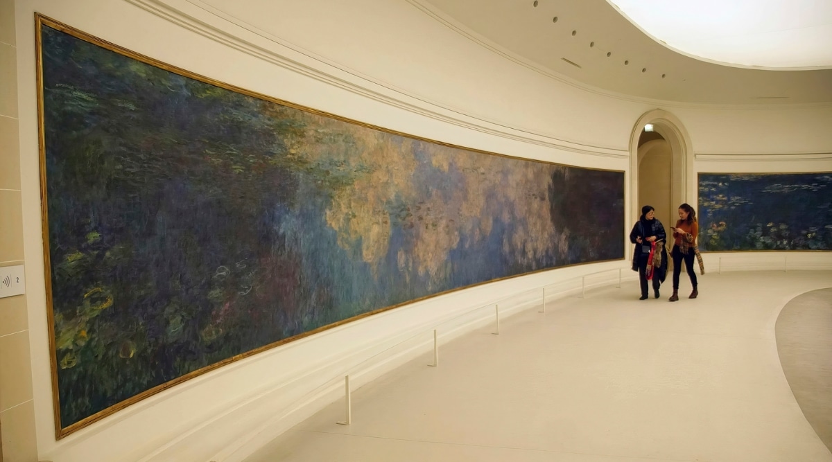 Visitors admiring Claude Monet's famous giant water lily oil paintings in The Musee de l'Orangerie in Paris France.