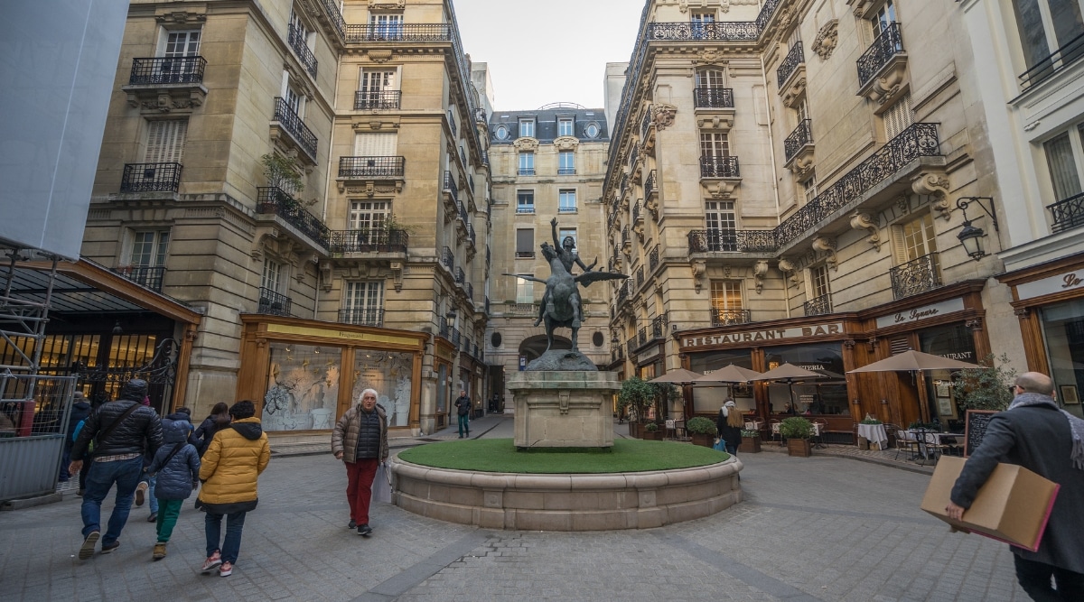 The courtyard entrance to Musee du Parfum Fragonard with a statue in the center and tourists coming and going.