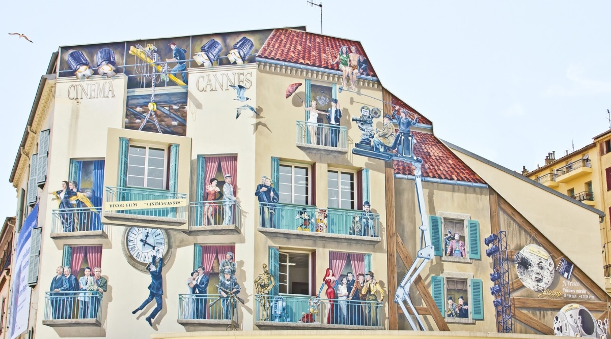 The famous Painted Walls of Cannes France, a large mural painted near a bus stop depicting numerous famous characters and celebrities.