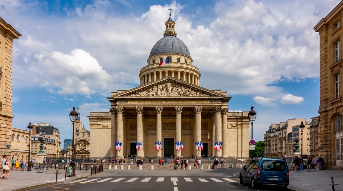 The Pantheon in Paris France, photographed from the street as tourists admire the destination on a bright sunny day. 