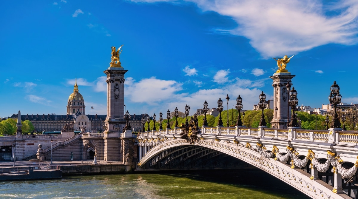 The Pont Alexandre III bridge photographed from the side view with all the ornate gold statues shining in the bright summer sunlight. 