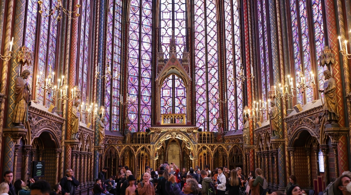 Saint-Chapelle interior in Paris France filled with tourists admiring the unique stained glass window panes.