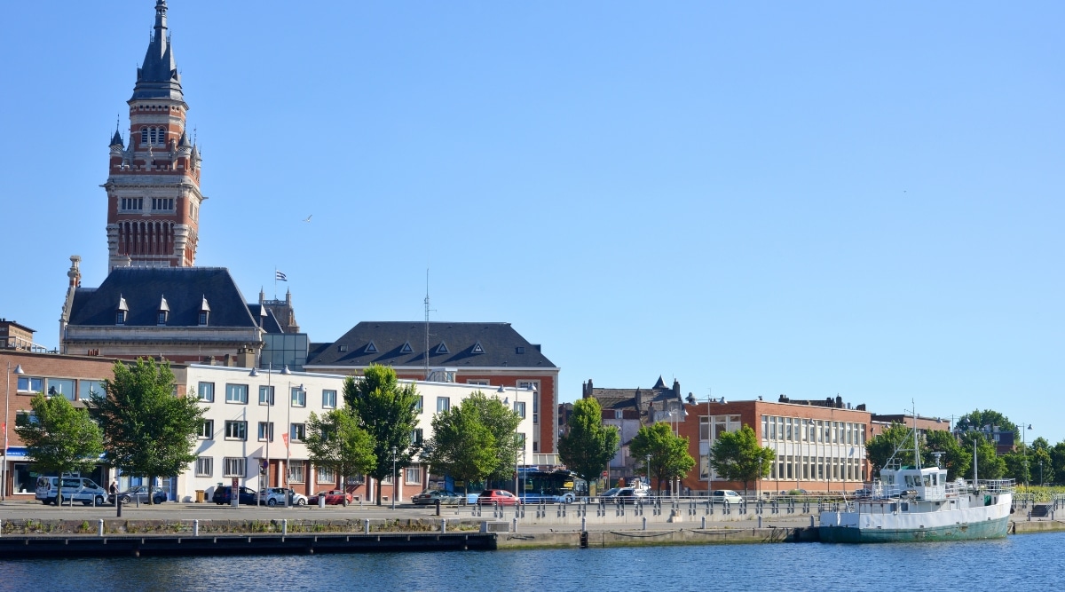 A side view capturing the Town Hall of Dunkirk, featuring architectural details in a straightforward composition. The image showcases the exterior facade of the Town Hall, highlighting its characteristic design elements. Neutral weather conditions are evident.