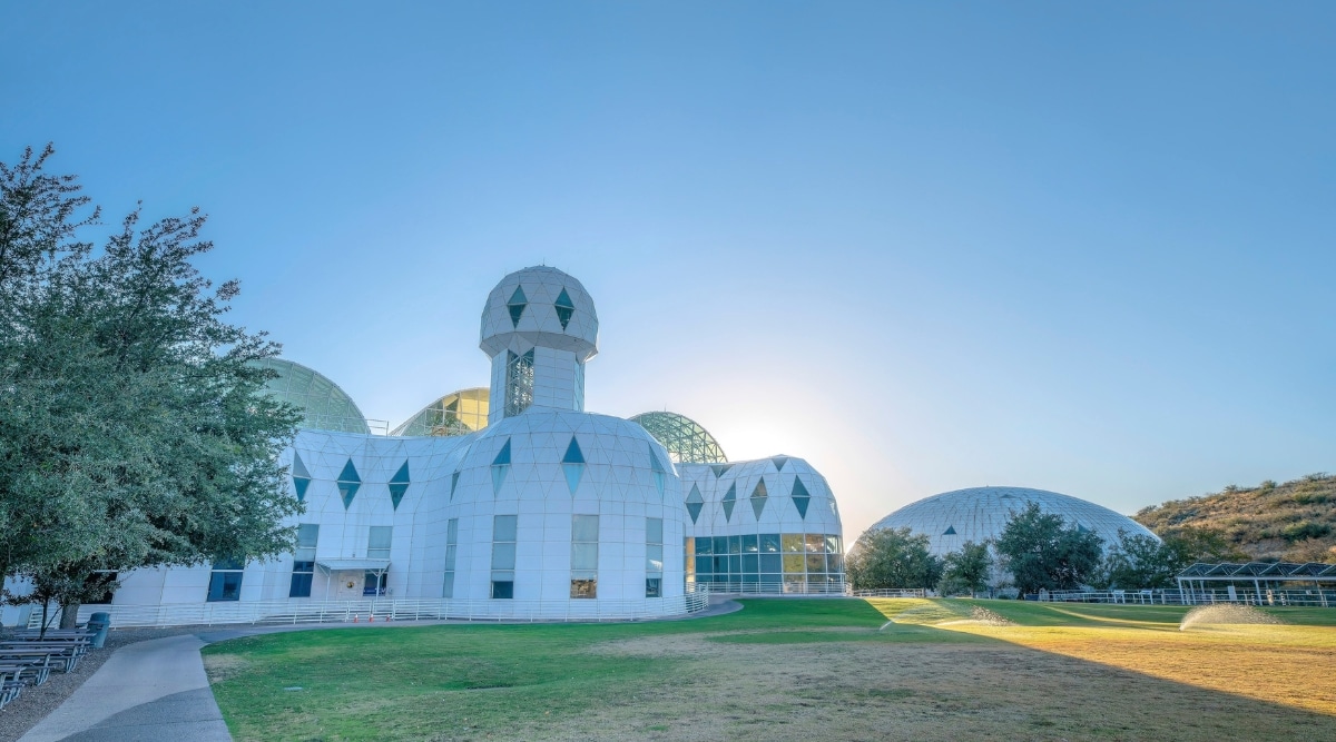 Biosphere 2, situated in Oracle, Arizona. The image provides a striking perspective of the colossal glass-enclosed structure. The impressive biomes and geodesic glass domes stand in stark contrast to the surrounding desert.