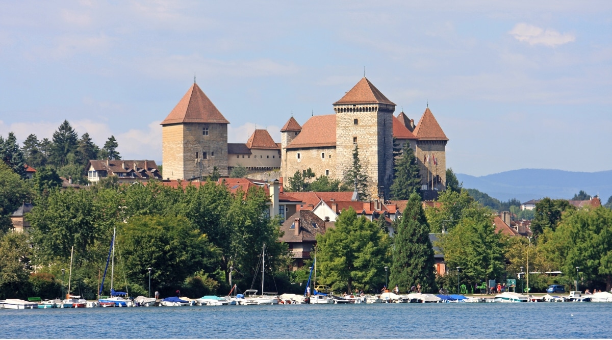 View of Chateau d'Annecy. The Chateau d'Annecy is a magnificent historical castle perched atop a hill overlooking the town of Annecy. Its imposing stone walls and turrets harken back to the medieval era. The castle's picturesque location against the backdrop of the French Alps, along with its beautifully landscaped gardens, adds to its charm.