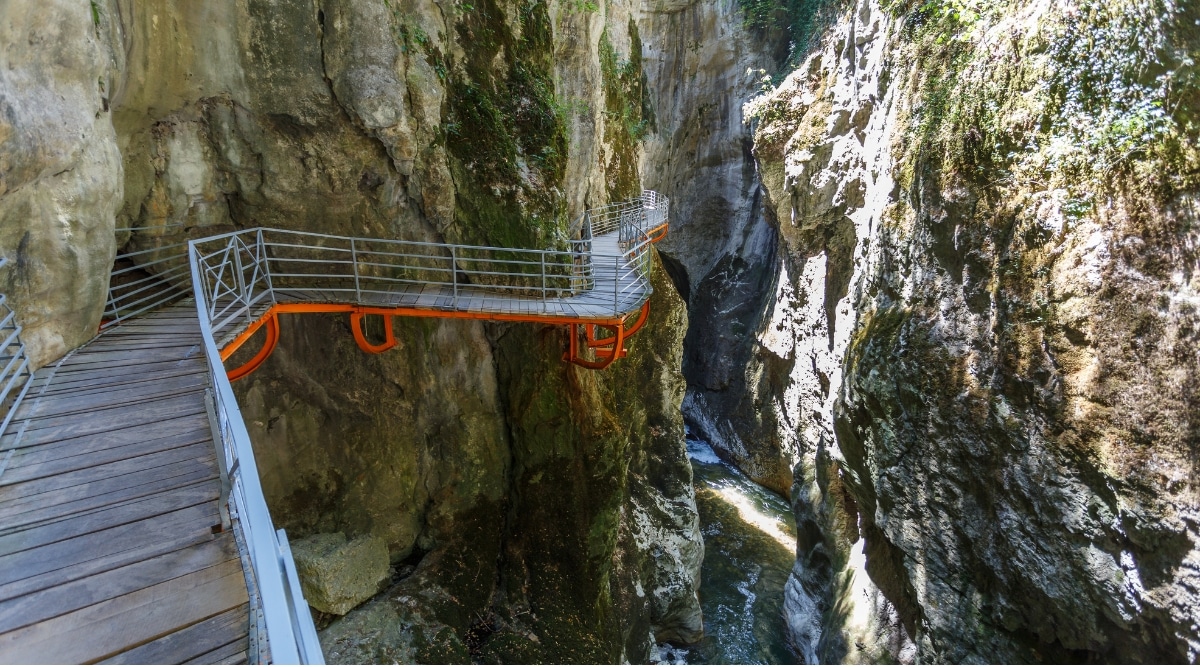 An enchanting photograph of the Gorges du Fier, a stunning natural wonder in the Rhône-Alpes region of France. The image reveals the deep gorge carved by the Fier River, with towering rock formations and crystal-clear waters.