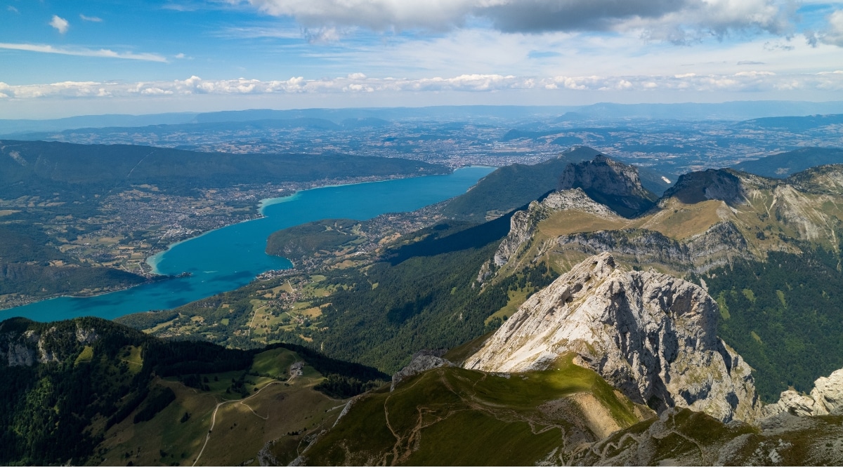 A breathtaking photograph of La Tournette Peak, a prominent mountain in the French Alps.This image captures the rugged majesty of the rocky summit as it looms over Lake Annecy, with a lengthy ridge adorned by numerous winding trails.