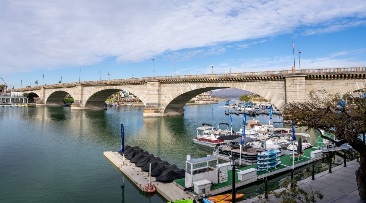 The image showcases the city nestled along the sparkling shores of Lake Havasu, with the iconic London Bridge stretching across the tranquil waters. Boats are visible on the lake, creating a sense of leisure and outdoor recreation. 