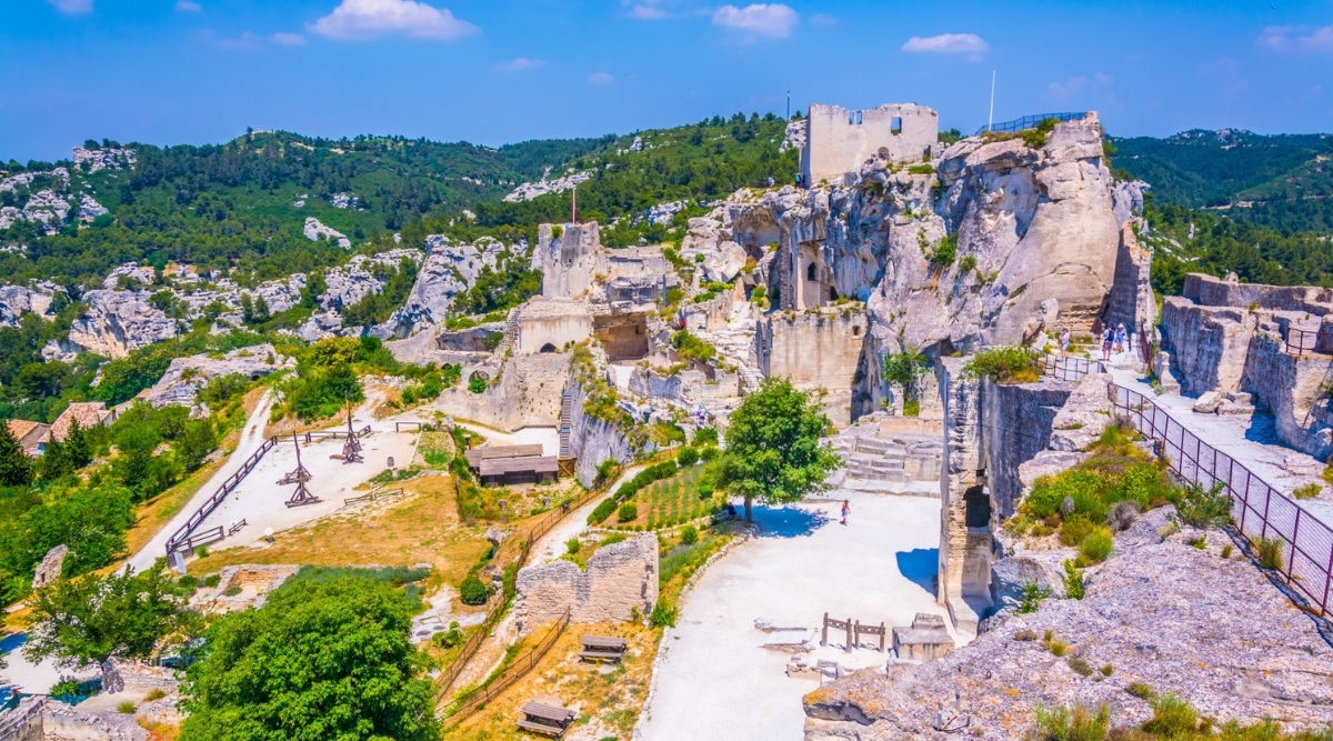 An enchanting view of Les Baux de Provence, a picturesque village perched atop rocky cliffs. The area captures the historic charm of this ancient town, featuring its well-preserved medieval architecture, winding cobblestone streets, and breathtaking panoramic vistas of the surrounding countryside. 