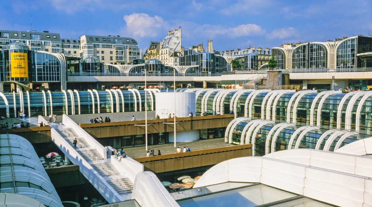 Aerial view of Les Halles. Les Halles, referring to a central market or shopping area in French city. The architecture of Les Halles features a combination of modern and traditional design elements. Modern market halls with large windows and sleek structures. The building has wide white staircases and wide sidewalks with people walking.
