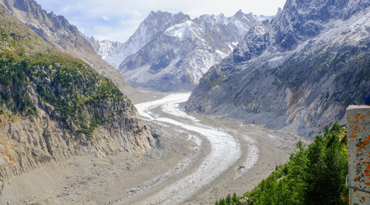 A breathtaking photograph of the Mer de Glace, the largest glacier in France nestled within the Mont Blanc Massif. This stunning glacier sprawls majestically between rugged mountains, glistening under the alpine sun. The vast icy expanses of the French Alps.