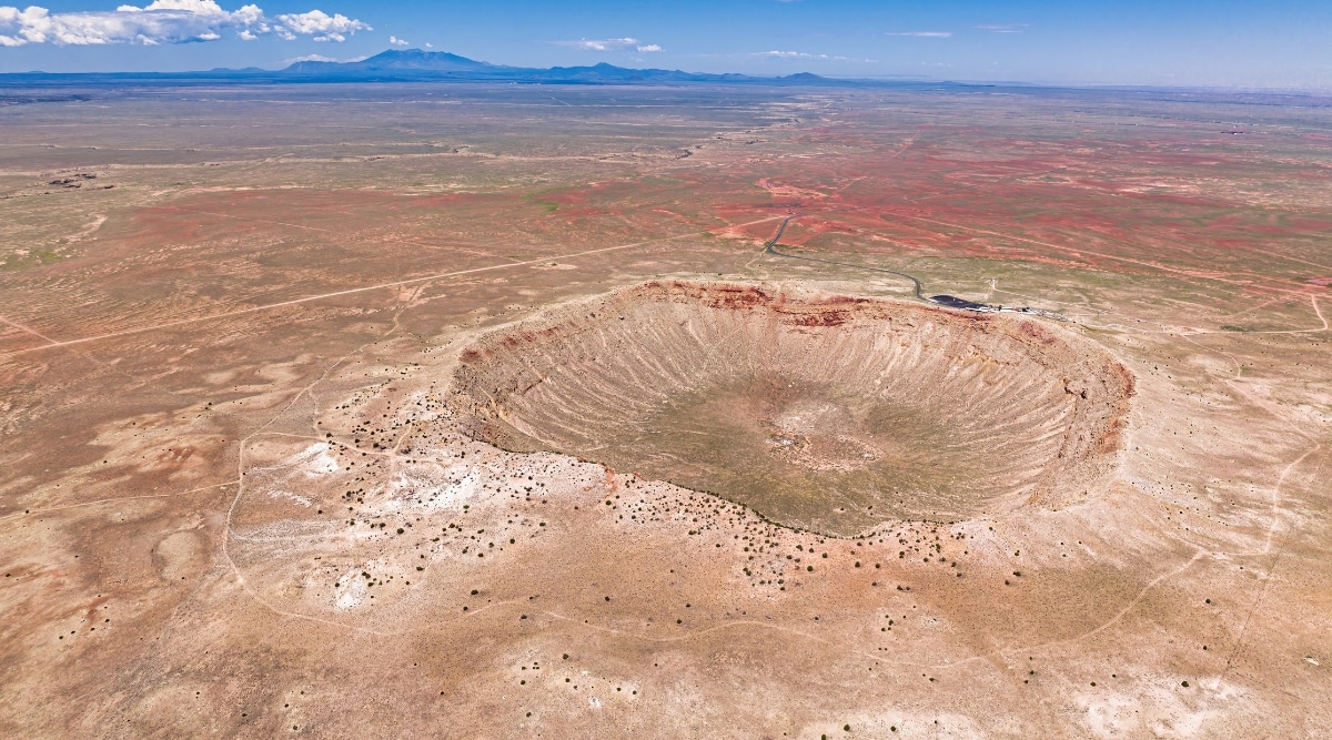 A captivating photo of Meteor Crater, a colossal impact site located near Winslow, Arizona. The image showcases the immense crater's bowl-like shape, surrounded by a stark and arid desert landscape.