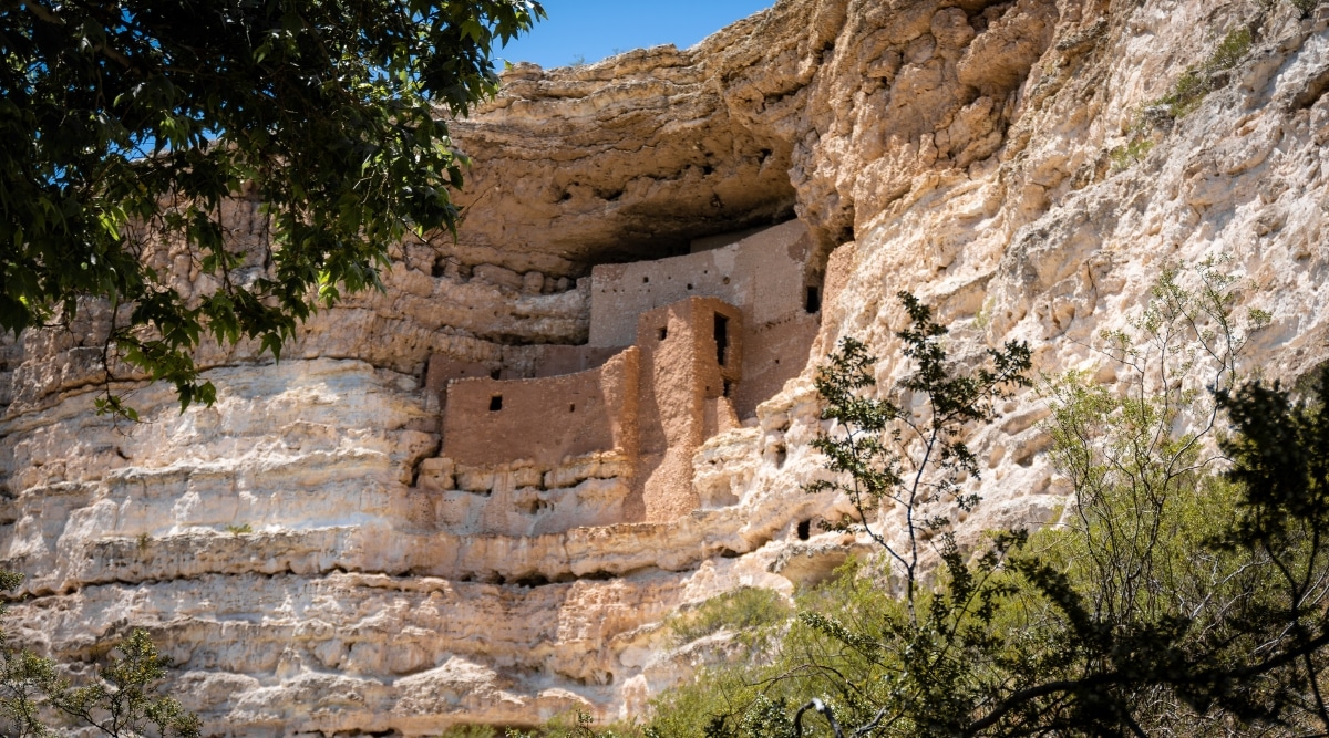 Montezuma Castle National Monument is a well-preserved historical site in Arizona, USA. The monument features a five-story limestone structure built into a limestone alcove, reminiscent of an ancient high-rise apartment building. This incredible architectural feat is framed by the surrounding lush greenery. The intricate details of the stone masonry and the well-preserved state of the site are truly remarkable.