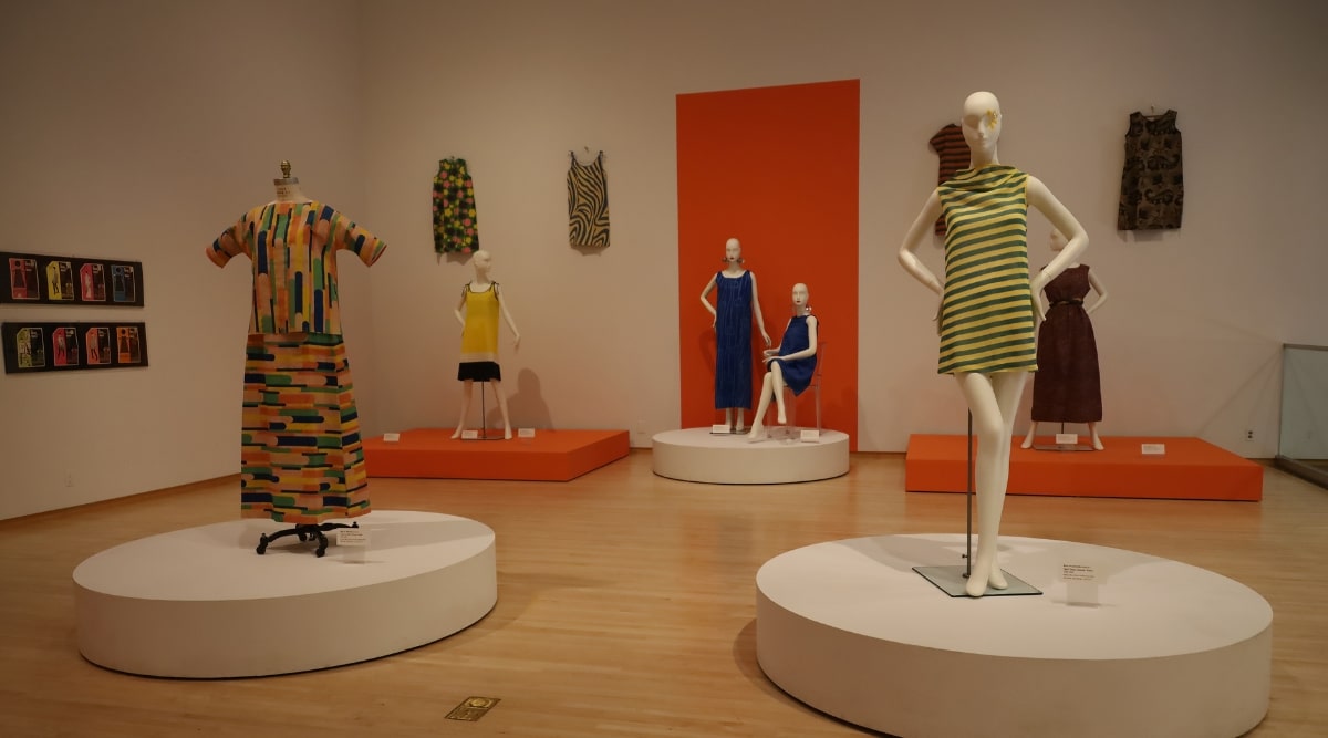 This image offers a glimpse inside the Phoenix Art Museum. The scene reveals a spacious and well-lit gallery with high ceilings and pristine white walls, providing the perfect canvas for showcasing a diverse array of artworks. The area is adorned with interactive installations showcasing clothing displayed on stands.