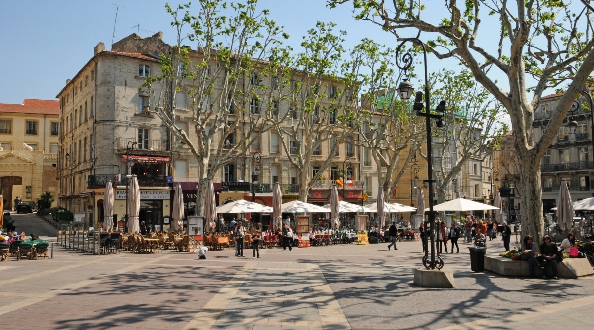 View of the Place de l'Horloge during daytime. The Place de l'Horloge is a captivating and bustling square in the heart of Avignon, France. It boasts a charming blend of architectural styles, buildings adorned with ornate facades, wrought-iron balconies, and colorful shutters.The square is framed by numerous outdoor cafes and restaurants with inviting terraces where people spend time.