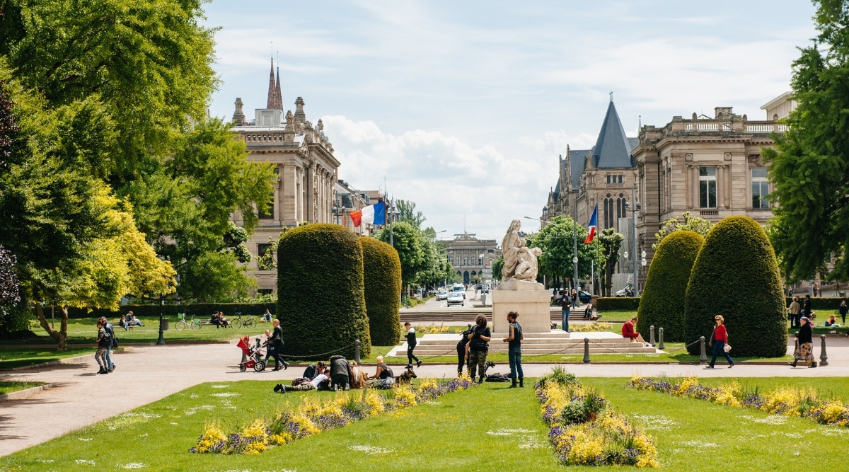 Place de la Republique in La Neustadt, Strasbourg, France. Tourists and locals alike out on the grass and walking the sidewalks.