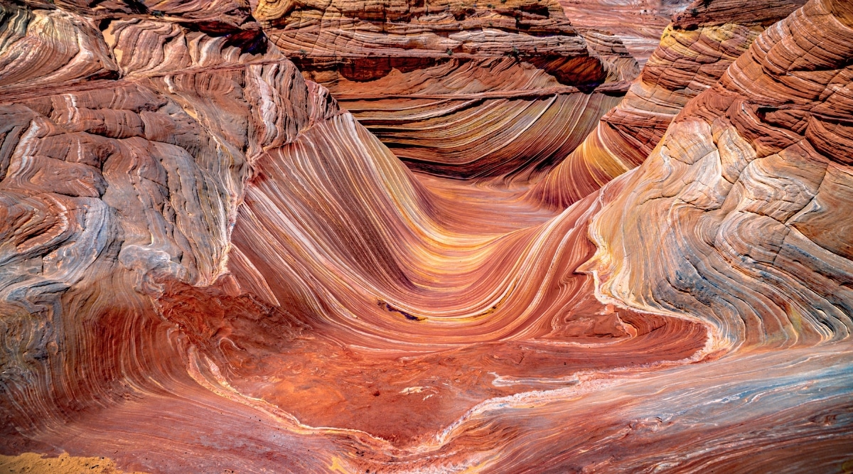 View from above of Vermilion Cliffs. The cliffs stand tall, exhibiting vibrant layers of sedimentary rock in various shades of red, orange, and white. 