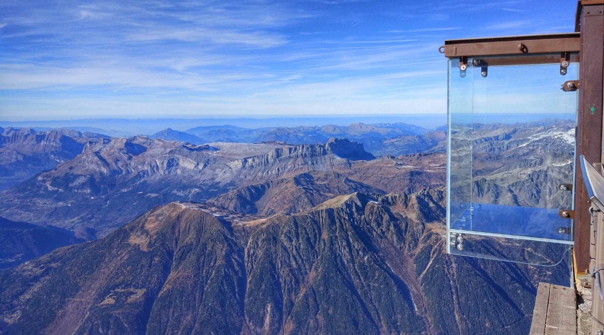 An exhilarating image captures the heart-pounding experience of the Step Into The Void – Aiguille du Midi Skywalk in Chamonix, France. Perched high in the French Alps, the skywalk is a transparent glass box extending from the Aiguille du Midi summit, offering an unparalleled view of the surrounding mountainous panorama. 
