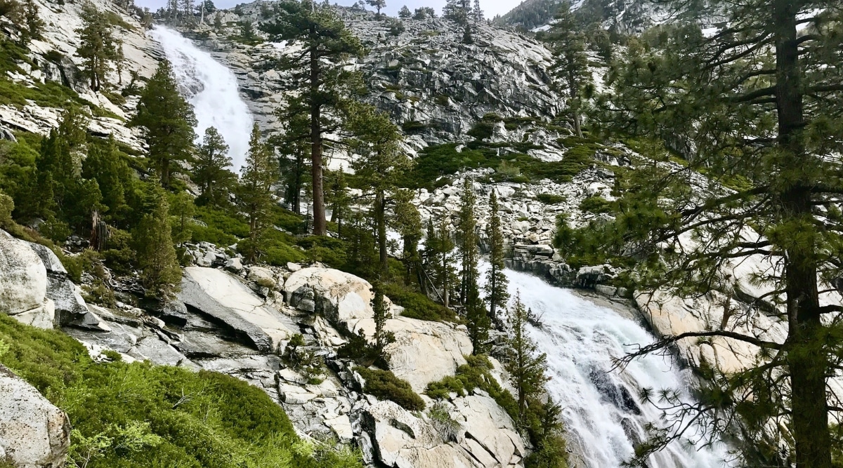 The photograph captures Horsetail Falls in California, depicting the waterfall against the rocky backdrop of the Sierra Nevada. The falls cascade down the granite cliffs, surrounded by sparse vegetation. The scene is framed by the rugged terrain of the mountainous landscape. 