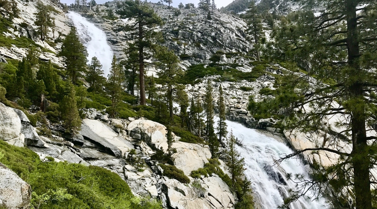 The photograph captures Horsetail Falls in California, depicting the waterfall against the rocky backdrop of the Sierra Nevada. The falls cascade down the granite cliffs, surrounded by sparse vegetation. The scene is framed by the rugged terrain of the mountainous landscape.