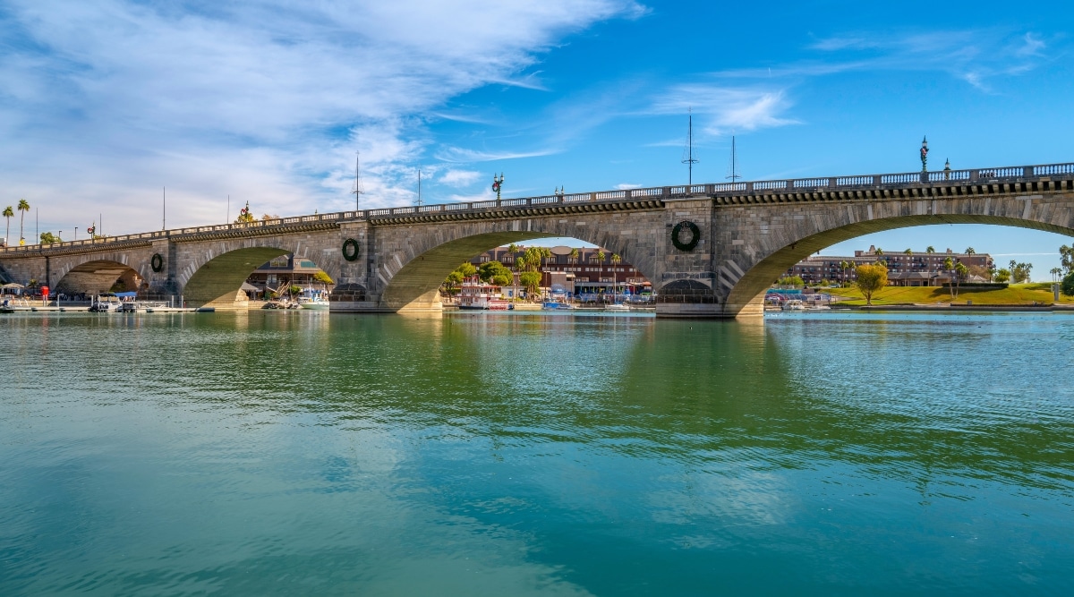 The image showcases the waters of Lake Havasu beneath a clear blue sky, with the classic architecture of London Bridge spanning majestically across the water.