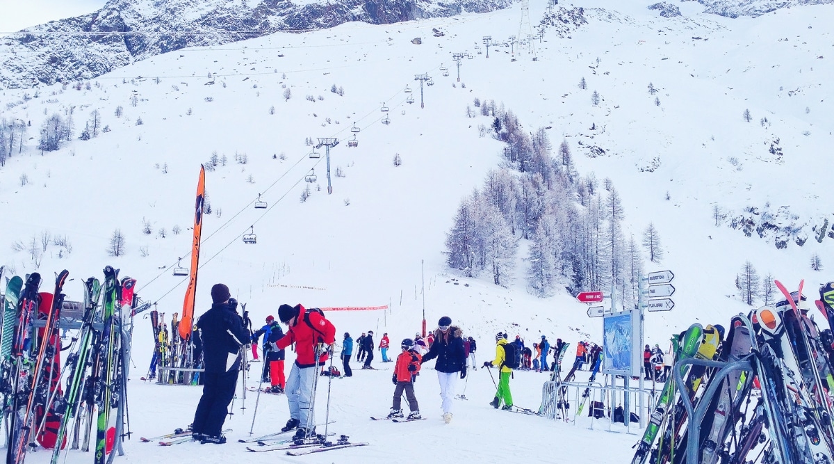 Les Grands Montets in Chamonix, France. Towering alpine peaks, dusted with a fresh layer of snow. Skiers and snowboarders, adorned in colorful gear, navigate the slopes with precision.