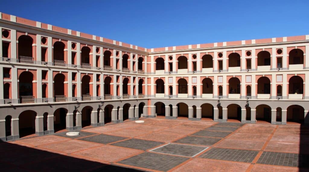 A photograph depicting the Museo de las Americas in Puerto Rico. The image showcases the exterior of the museum, featuring a traditional architectural style. The museum's facade exhibits a simple yet structured design.