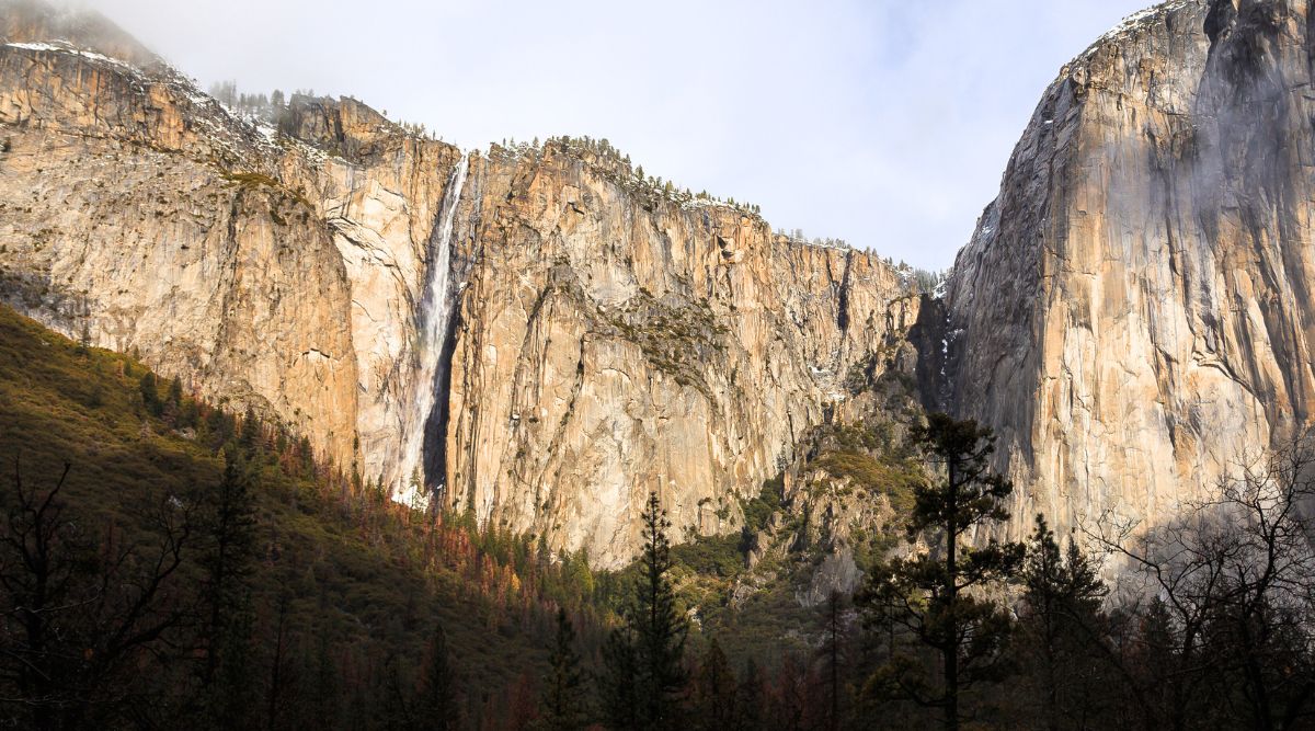 A photograph capturing Ribbon Falls in California. The image showcases the waterfall within a natural setting, surrounded by rocky terrain and vegetation. The falls cascade down a series of rock formations.