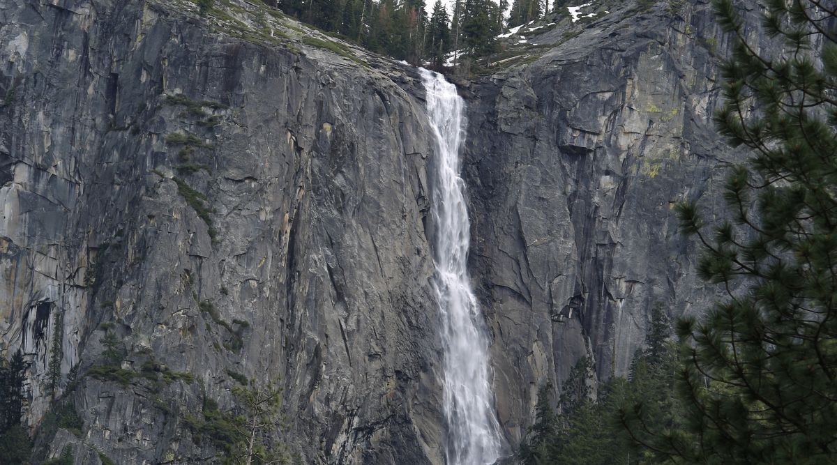 A photograph capturing Silver Strand Falls in California. The image showcases the waterfall against a rocky backdrop, surrounded by natural vegetation. The falls appear as a single-tier cascade, with water flowing over the rocky precipice. The scene is framed by the rocky terrain typical of the California landscape. 